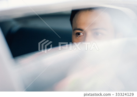 A businessman is looking outside from the view of his car A businessman is looking outside from the view of his car 33324129