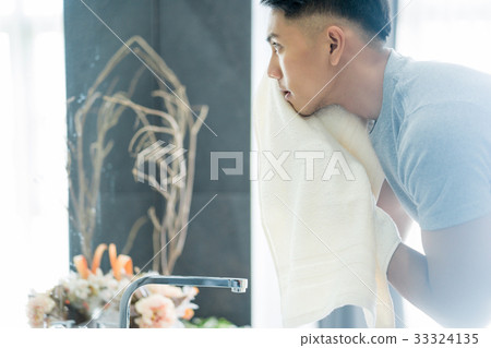 An asian man is using his towel and looking at the mirror in bathroom 33324135