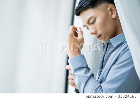 An asian man in shirt is standing beside the window 33324165