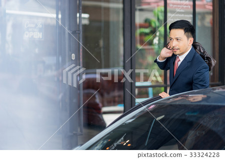 A portrait of young businessman closing a car door while looking at something. 33324228