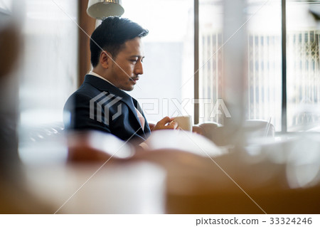 A photo of serious man drinking coffee while resting inside. 33324246