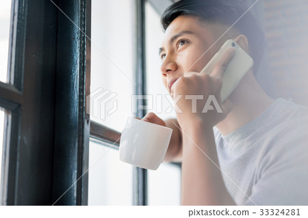 a photo of a man holding a cup, smiling and talking on the phone 33324281