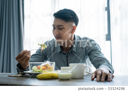 a picture of a man using the fork to eat breakfast 33324296