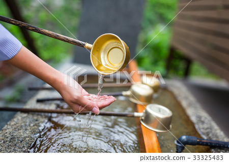 Woman washes her hand in fountain of Japanese temple 33325483