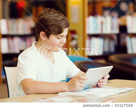 Teenage boy with tablet in library 33327568