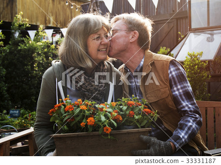 Senior Couple Man Giving Woman a Cheek Kiss and Flowers Senior Couple Man Giving Woman a Cheek Kiss and Flowers 33331187