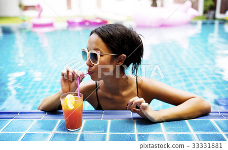 Asian woman drinking juice by the poolside 33331881