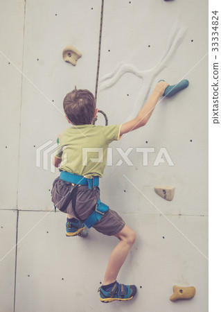 little boy climbing a rock wall outdoor. 33334824