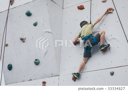 little boy climbing a rock wall outdoor. 33334827