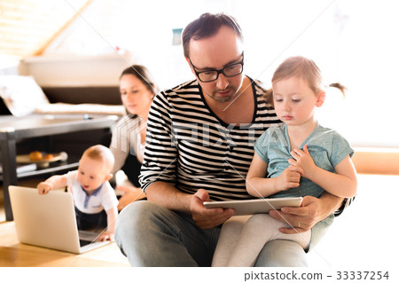 Young parents with little children and gadgets at Young parents with little children and gadgets at 33337254