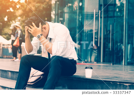 Workers man sitting headache in front of company Workers man sitting headache in front of company 33337347