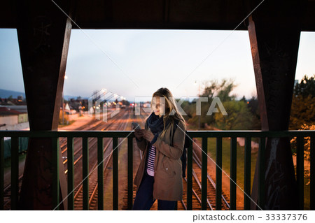 Woman in the city at night holding smartphone Woman in the city at night holding smartphone 33337376