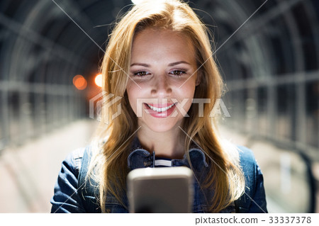 Woman in the city at night holding smartphone Woman in the city at night holding smartphone 33337378