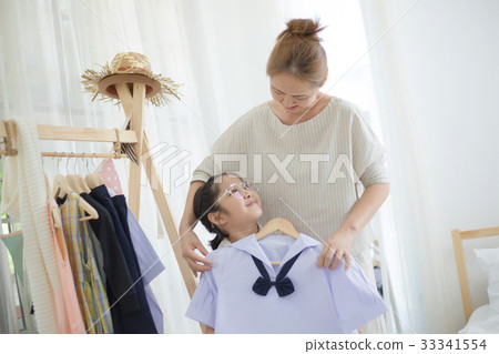Asian mother helping daughter dressing uniform Asian mother helping daughter dressing uniform 33341554