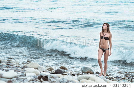 Young girl in swimsuit posing in sea with waves 33343294