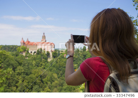 girl taking a picture of a beautiful castle on a hill 33347496