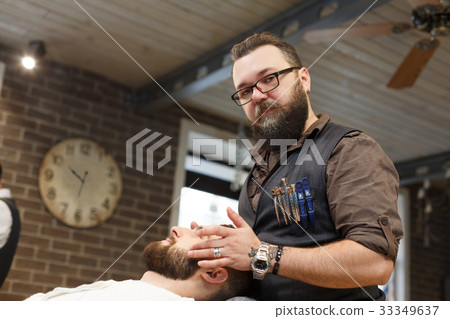 Man getting haircut by hairstylist at barbershop Man getting haircut by hairstylist at barbershop 33349637