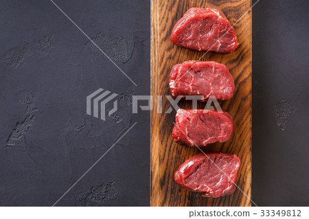 Raw beef filet mignon steaks on wooden board at Raw beef filet mignon steaks on wooden board at 33349812