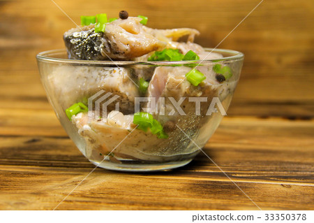 Marinated carp in glass bowl on wooden table 33350378