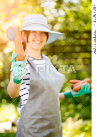 Brunette in hat holding carrot 33367387
