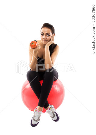 Girl is sitting on the fitness ball and holding a tomato Girl is sitting on the fitness ball and holding a tomato 33367666