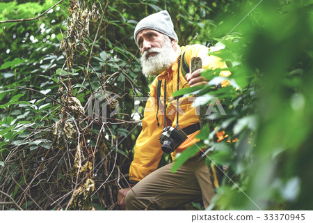 Thoughtful senior male hiker walking in wild Thoughtful senior male hiker walking in wild 33370945