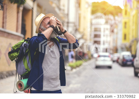 Calm senior man using camera in city Calm senior man using camera in city 33370982