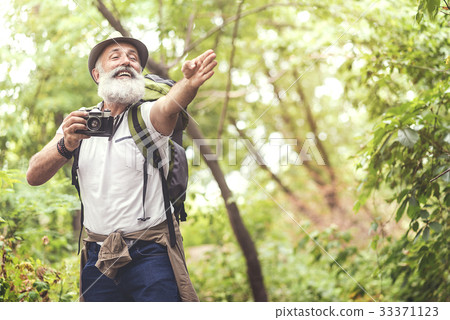 Joyful old man taking photos in forest 33371123