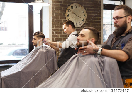 Man getting haircut by hairstylist at barbershop Man getting haircut by hairstylist at barbershop 33372467