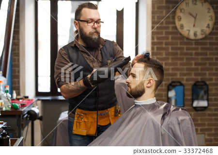 Man getting haircut by hairstylist at barbershop Man getting haircut by hairstylist at barbershop 33372468