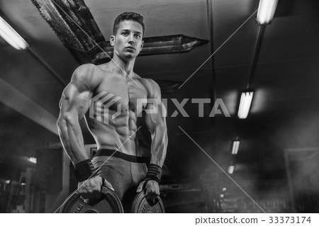 Handsome man with big muscles, posing at the camera in the gym 33373174