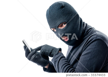 Hacker hacks data from a mobile phone on a white Hacker hacks data from a mobile phone on a white 33374433