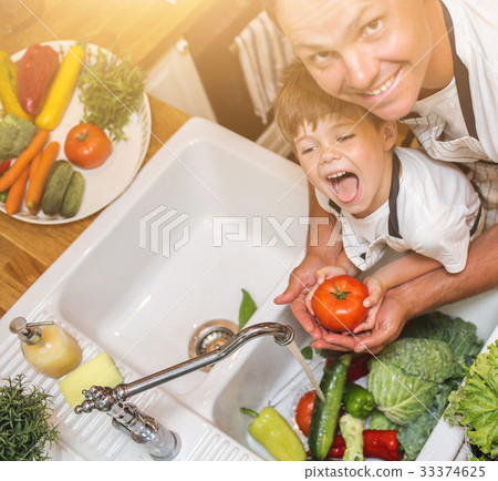 Father with son washes vegetables before eating 33374625