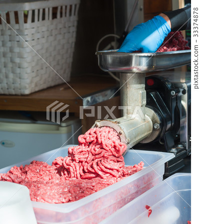 Tray of chopped meat, meat mincer, butcher's hand. 33374878