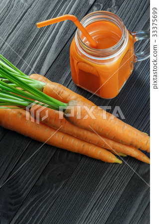 Carrot juice in a glass jar with handle on table Carrot juice in a glass jar with handle on table 33375699