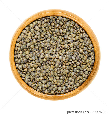 Puy lentils in wooden bowl over white 33376139