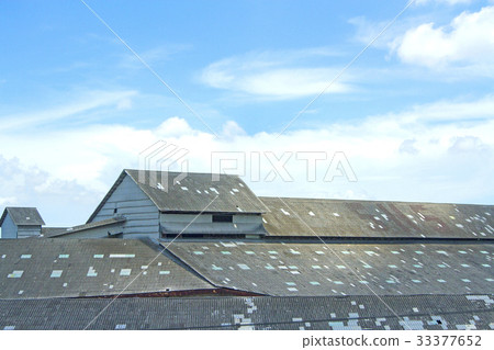 The roof of an old warehouse in the blue sky. The roof of an old warehouse in the blue sky. 33377652