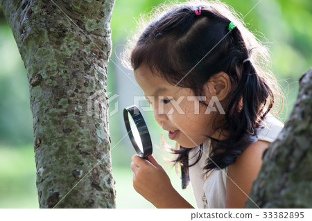 asian girl looking through a magnifying glass asian girl looking through a magnifying glass 33382895