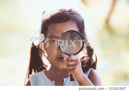 asian girl looking through a magnifying glass asian girl looking through a magnifying glass 33382897