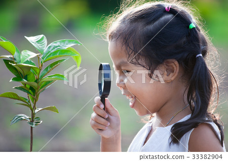 asian girl looking through a magnifying glass 33382904