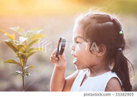 asian girl looking through a magnifying glass 33382905