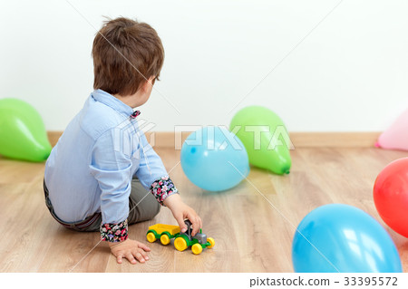 Little boy playing with toy cars on the floor 33395572