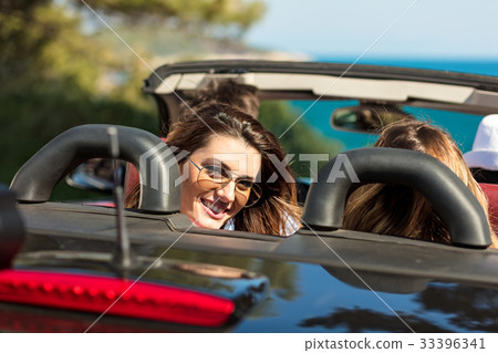 Group of cheerful young friends driving car and 33396341