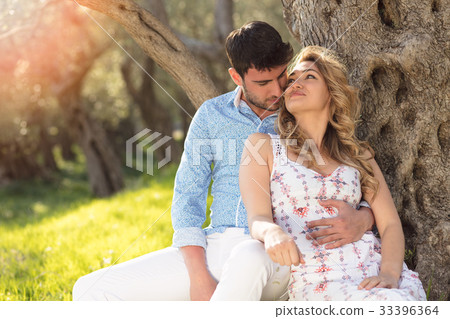 Loving young couple standing by trees at olive 33396364