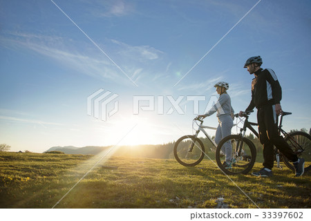 Cyclist couple with mountain bikes standing on the Cyclist couple with mountain bikes standing on the 33397602