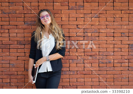 Girl with a tablet near a brick wall 33398210