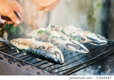 man checks the fish on the grill for readiness 33404887
