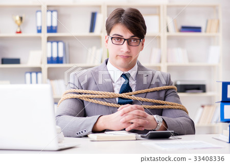 Businessman tied up with rope in office Businessman tied up with rope in office 33408336