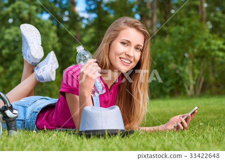 Young woman using her smart phone at the park Young woman using her smart phone at the park 33422648