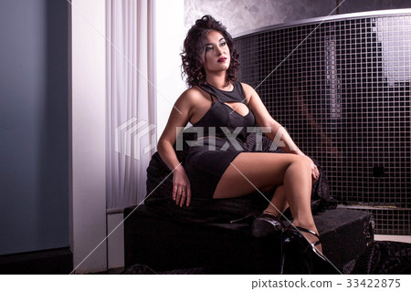 Pretty woman in a short black dress sitting on a Pretty woman in a short black dress sitting on a 33422875